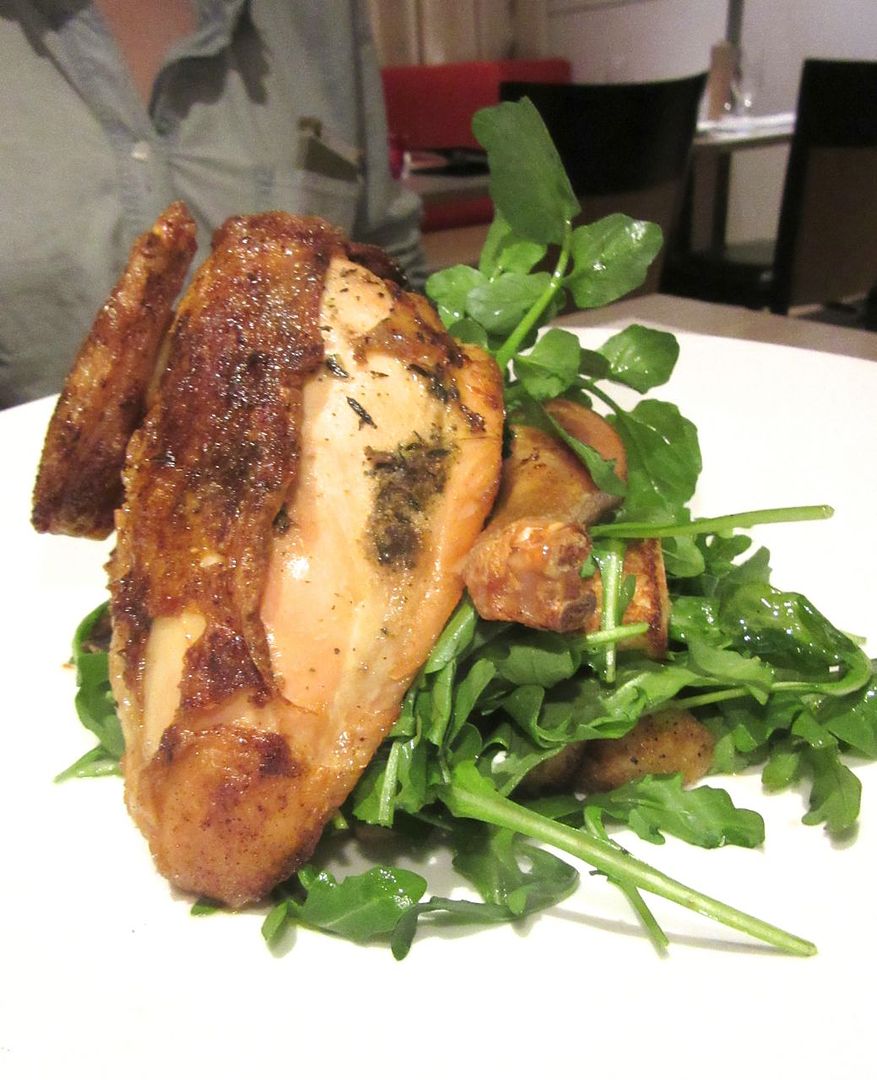 Trattoria Bianca’s rotisserie chicken sits on bread salad with raisins and pine nuts.